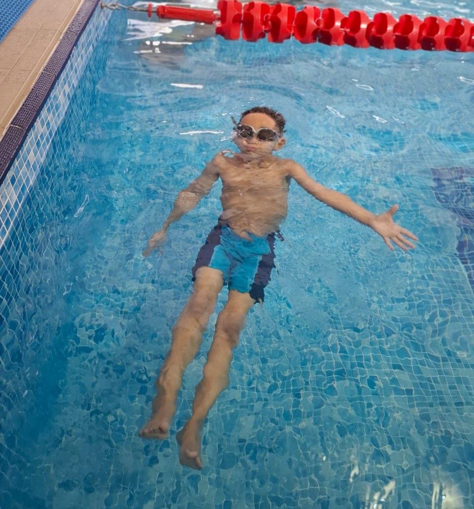 A child floating on his back wearing goggles